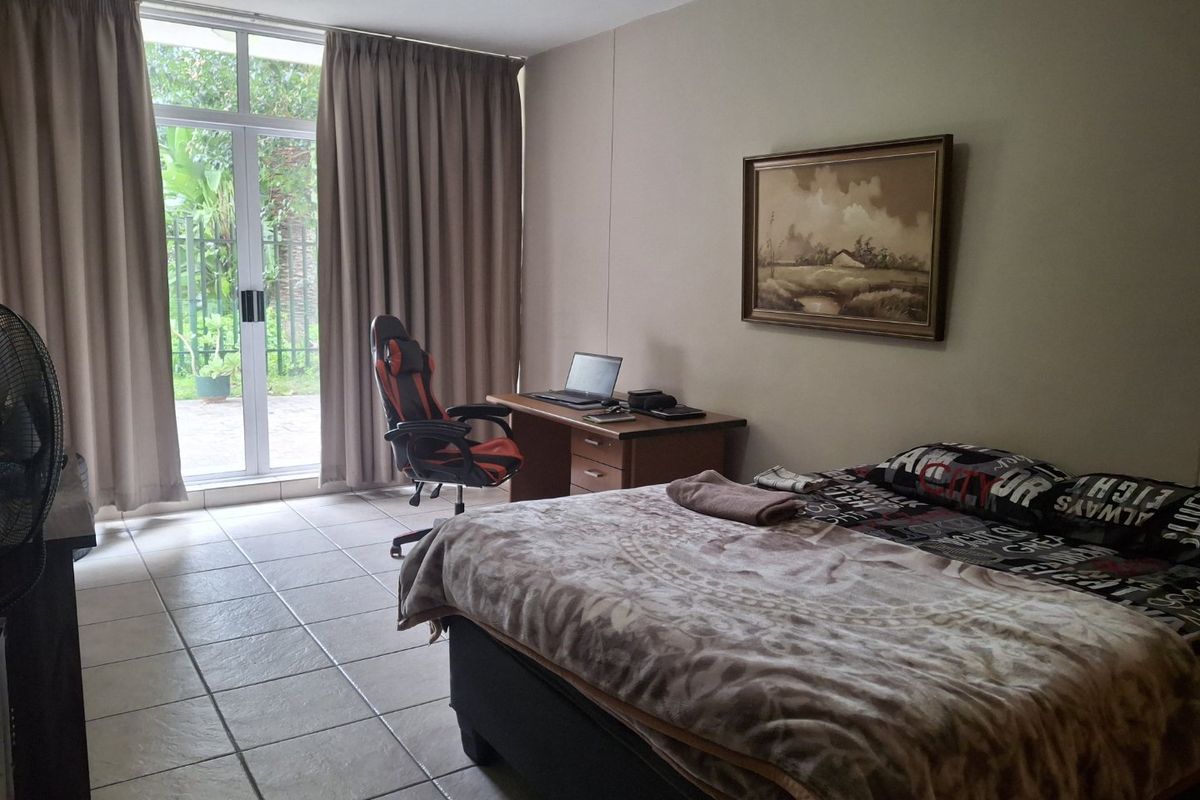 A bedroom featuring tiled flooring and a sliding glass door providing access to the exterior, offering natural light and a functional layout.