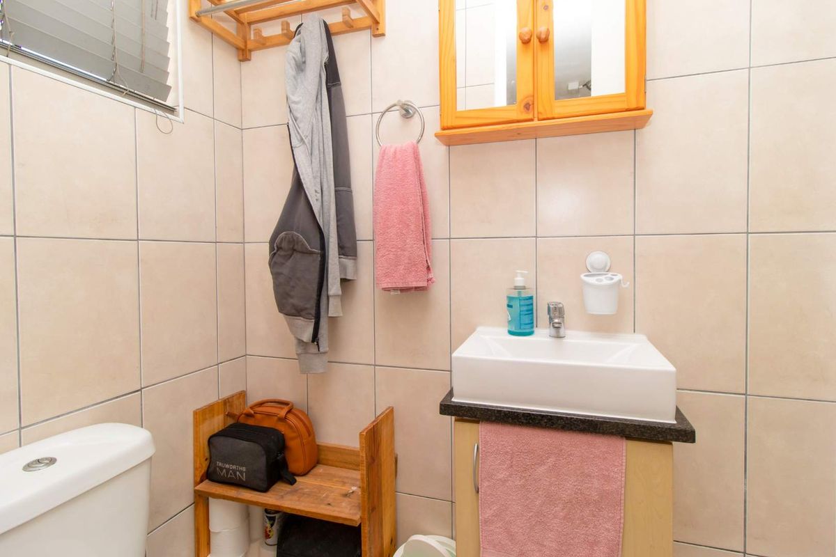 A compact bathroom featuring a wall-mounted vanity with a basin, a toilet, and tiled walls.