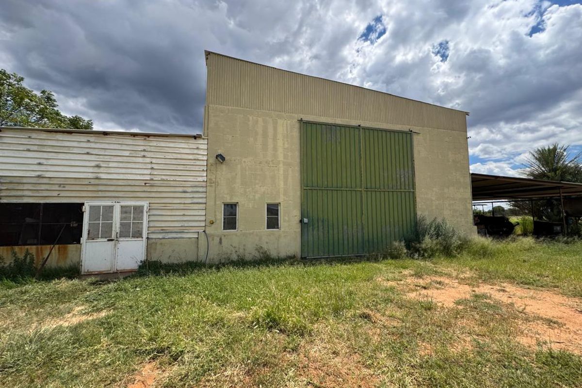 Exterior view of a large farm utility building featuring corrugated metal siding, a large sliding door, and a secondary entrance with double doors.