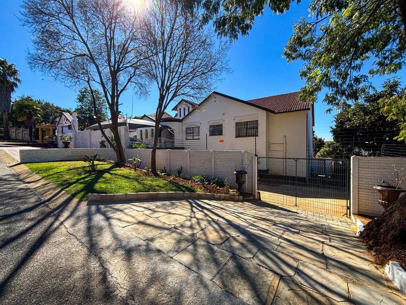 Front view of the property featuring a stone paved driveway, perimeter wall with electric fencing, and a secure metal gate entrance.