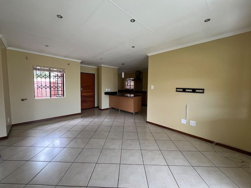 Spacious open-plan living area featuring tiled flooring, recessed lighting, and a functional kitchen with granite countertops and built-in cabinetry.