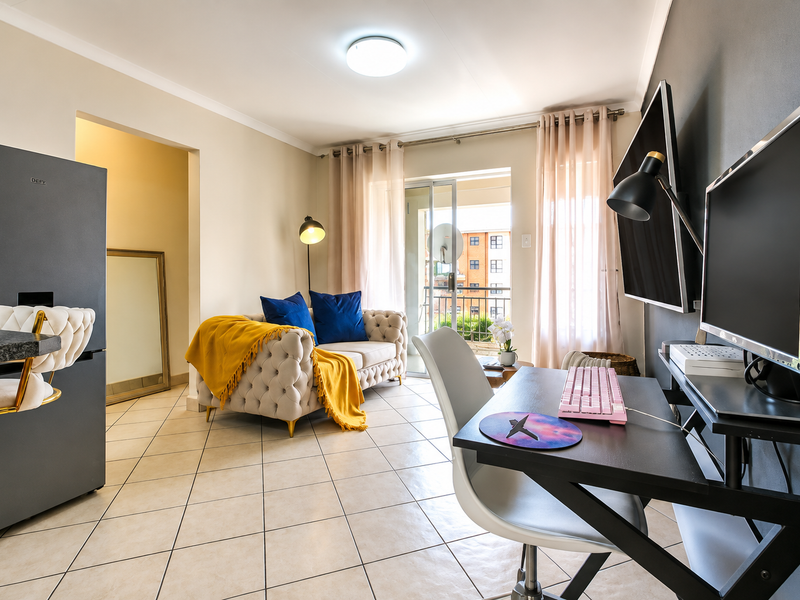 An open-plan living area featuring tiled flooring, neutral walls, and a sliding glass door providing access to a private balcony.