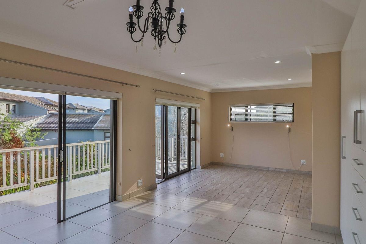 Spacious, light-filled living area featuring neutral tiled floors, built-in cabinetry, and dual sliding glass doors providing seamless access to an outdoor balcony.
