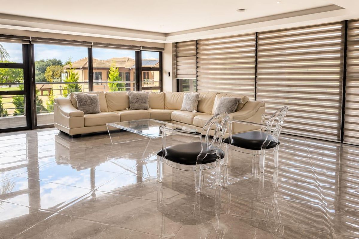 Spacious living area featuring large format polished porcelain floor tiles, expansive sliding glass doors, and modern roller blinds providing ample natural light.