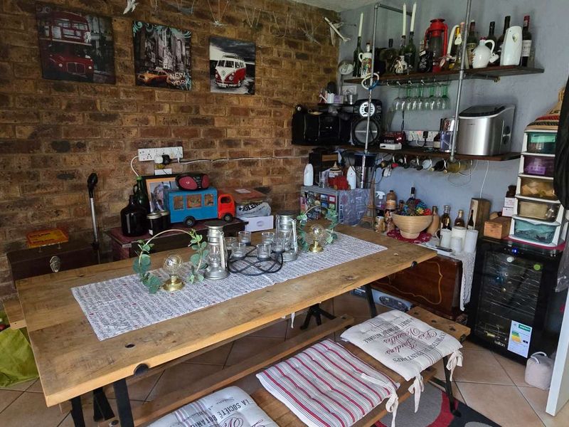 Dining area featuring an exposed brick wall and tiled flooring, currently utilized as a casual entertainment space adjacent to the garage.