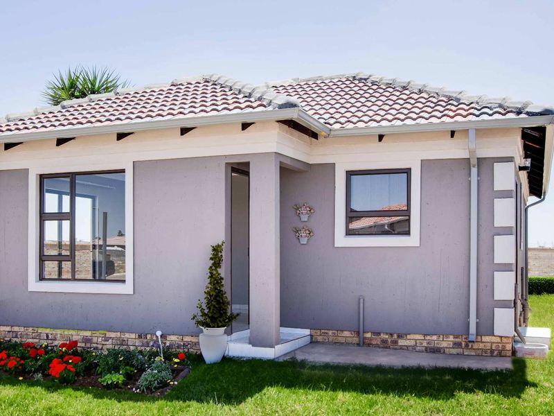 A well-maintained single-story residential home featuring a tiled roof, grey rendered facade, and aluminium window frames set within a neat garden.