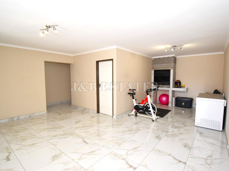 Spacious living area featuring polished marble-look floor tiles, a built-in fireplace, and neutral wall finishes, offering a versatile open-plan layout.