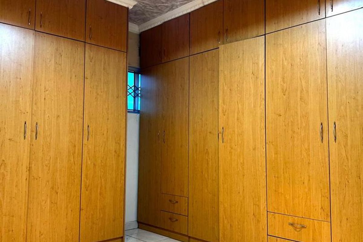 A bedroom featuring extensive floor-to-ceiling built-in wooden cabinetry, tiled flooring, and a decorative textured ceiling with recessed lighting.