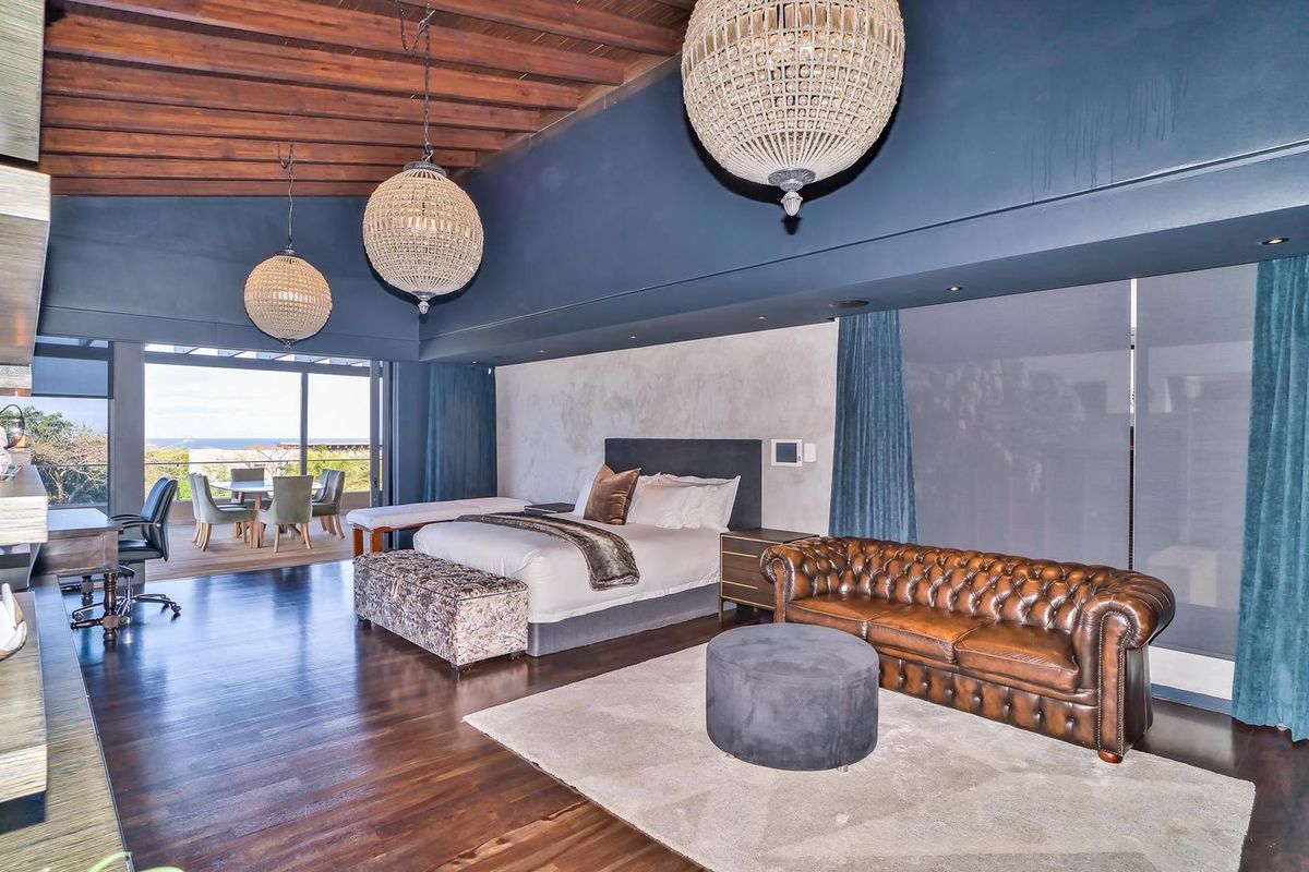 Spacious bedroom featuring exposed timber beam ceilings, hardwood flooring, and large sliding glass doors opening to an outdoor patio area.