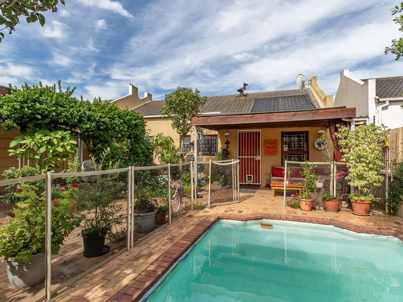 Rear garden area featuring a swimming pool with brick coping, a paved patio, and a timber pergola attached to the main dwelling.