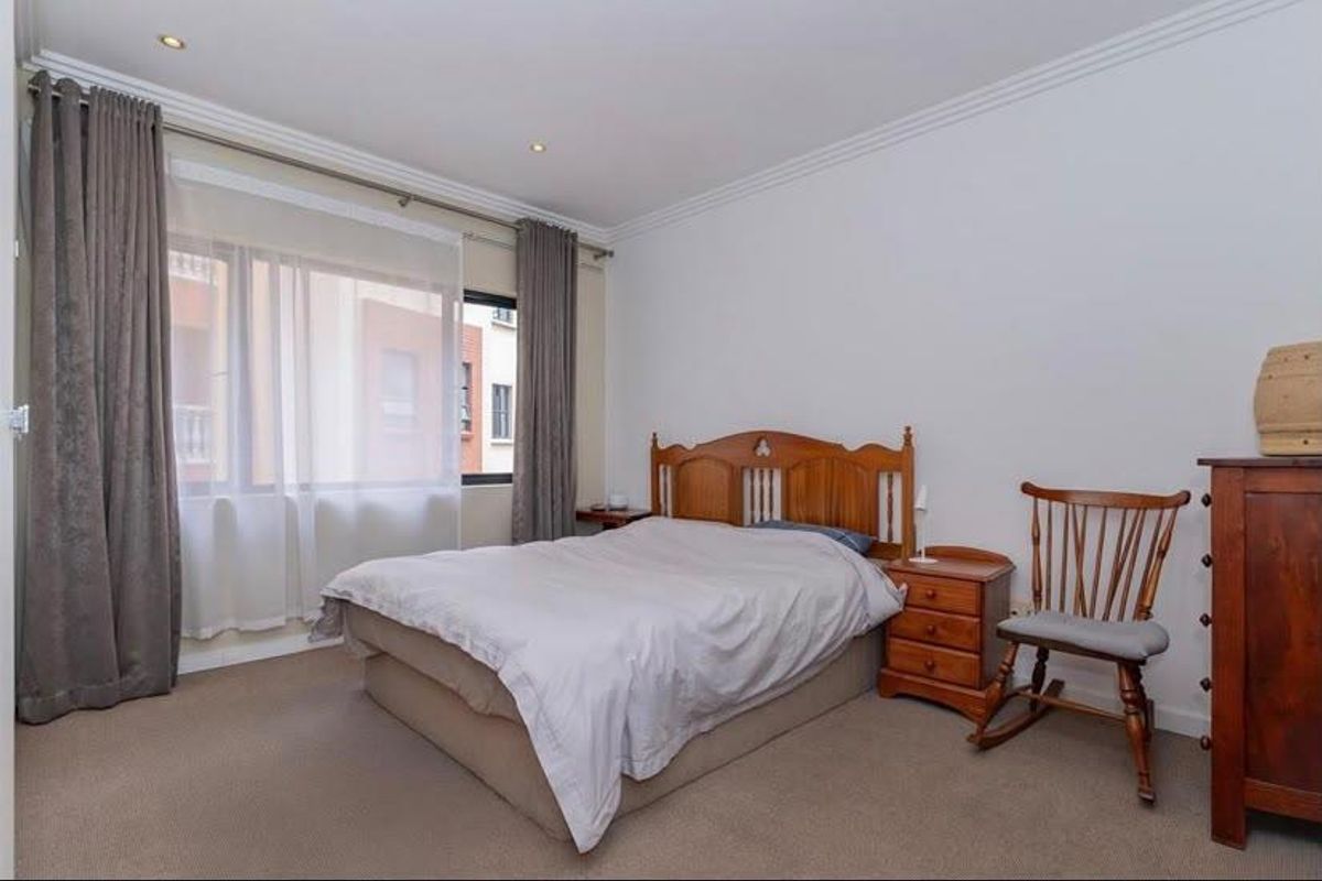 A well-proportioned bedroom featuring neutral carpeting, recessed downlighting, and decorative cornice detailing, offering a comfortable and functional living space.