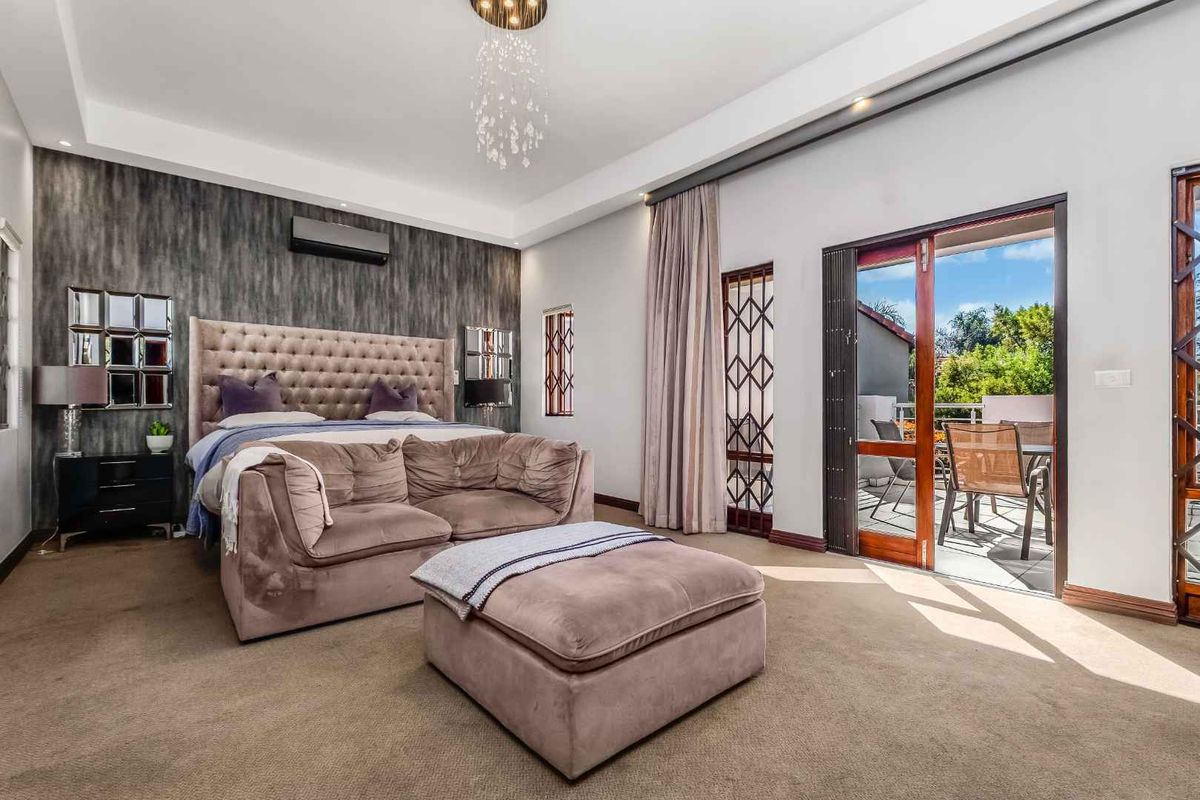 Spacious bedroom featuring a recessed ceiling, split-system air conditioning, and direct access to a private balcony through sliding glass doors.