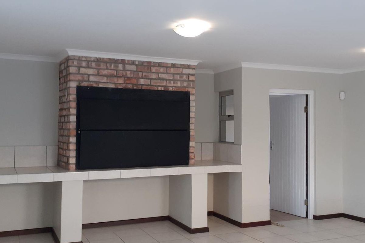 A living area featuring a built-in brick fireplace and tiled hearth, with neutral wall finishes and tiled flooring throughout.
