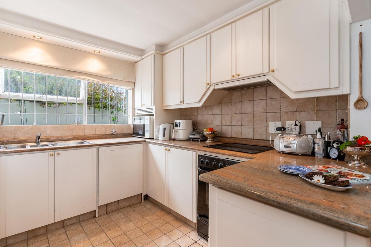 A functional kitchen featuring white cabinetry, stone countertops, a tiled backsplash, and integrated cooking appliances, offering a classic layout with ample storage space.