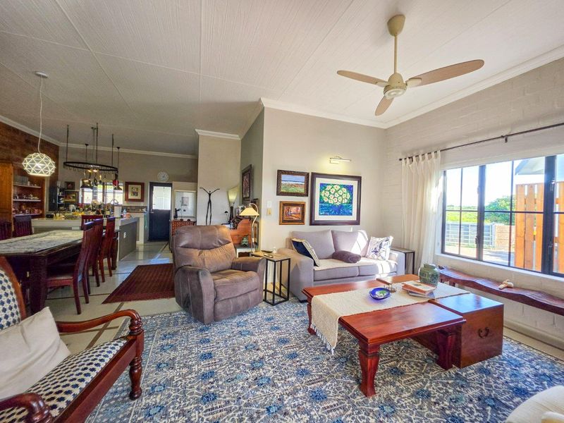 Spacious open-plan living and dining area featuring a kitchen island, ceiling fan, and large windows that provide ample natural light.