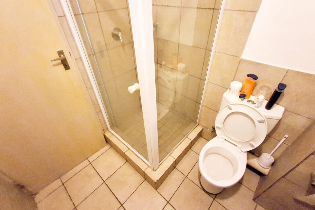 Compact bathroom featuring a corner shower enclosure with glass doors and a standard white toilet.
