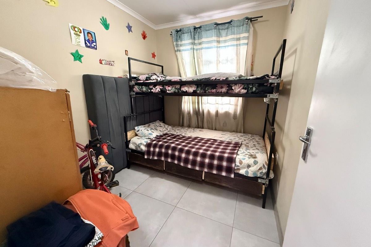 A functional bedroom featuring tiled flooring and a window with curtain tracks.