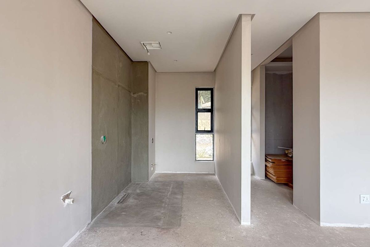 An unfinished interior space featuring exposed plumbing rough-ins, bare concrete flooring, and partition walls, ready for final finishes and fixtures.