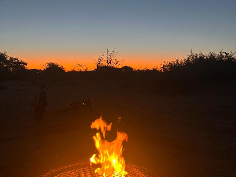 A scenic evening view of the property grounds featuring a built-in fire pit area under a sunset sky.