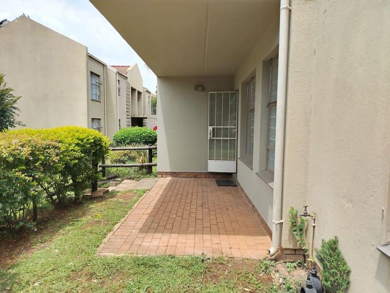 A covered brick-paved patio area featuring a security gate and external water tap, providing direct access to the garden space.