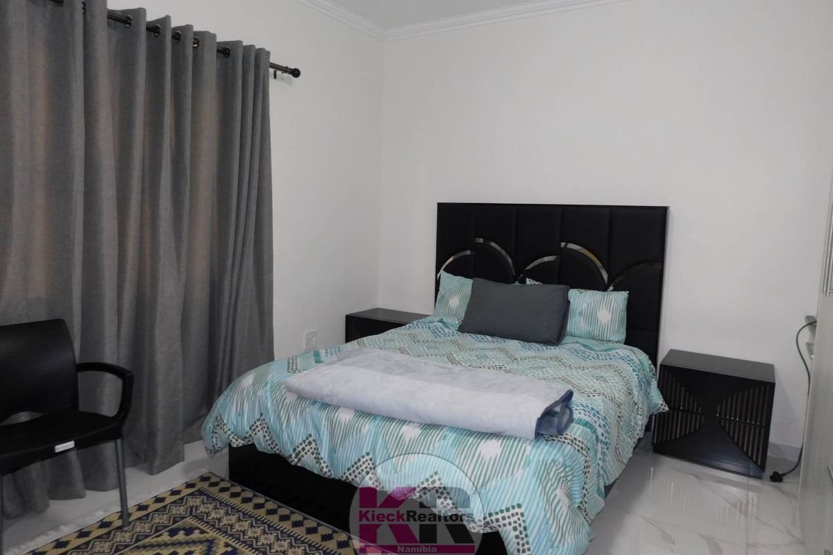 A well-maintained bedroom featuring tiled flooring, neutral walls, and crown molding, providing a clean and functional living space.