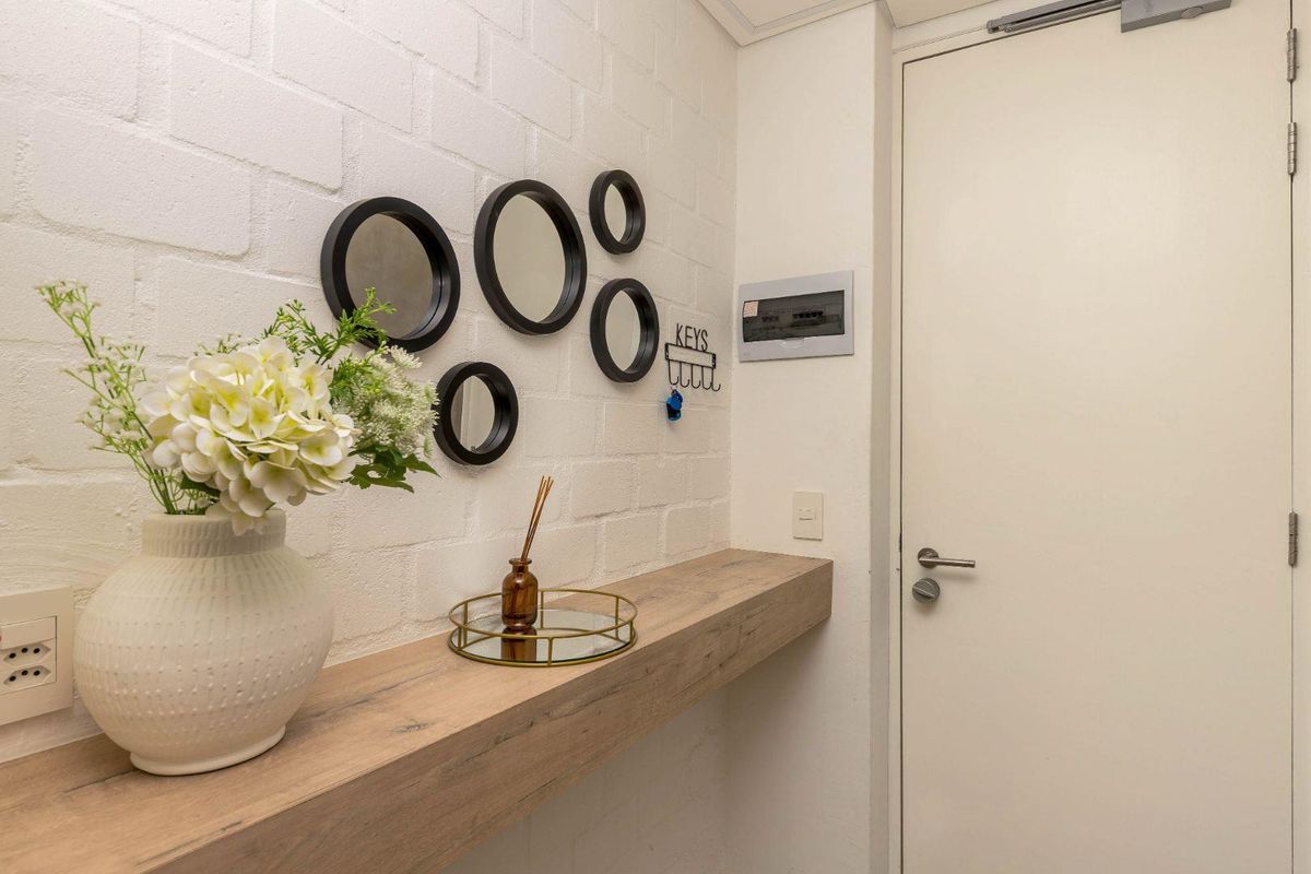 A clean entry area featuring a white exposed brick wall, a modern floating timber shelf, and a secure internal door.