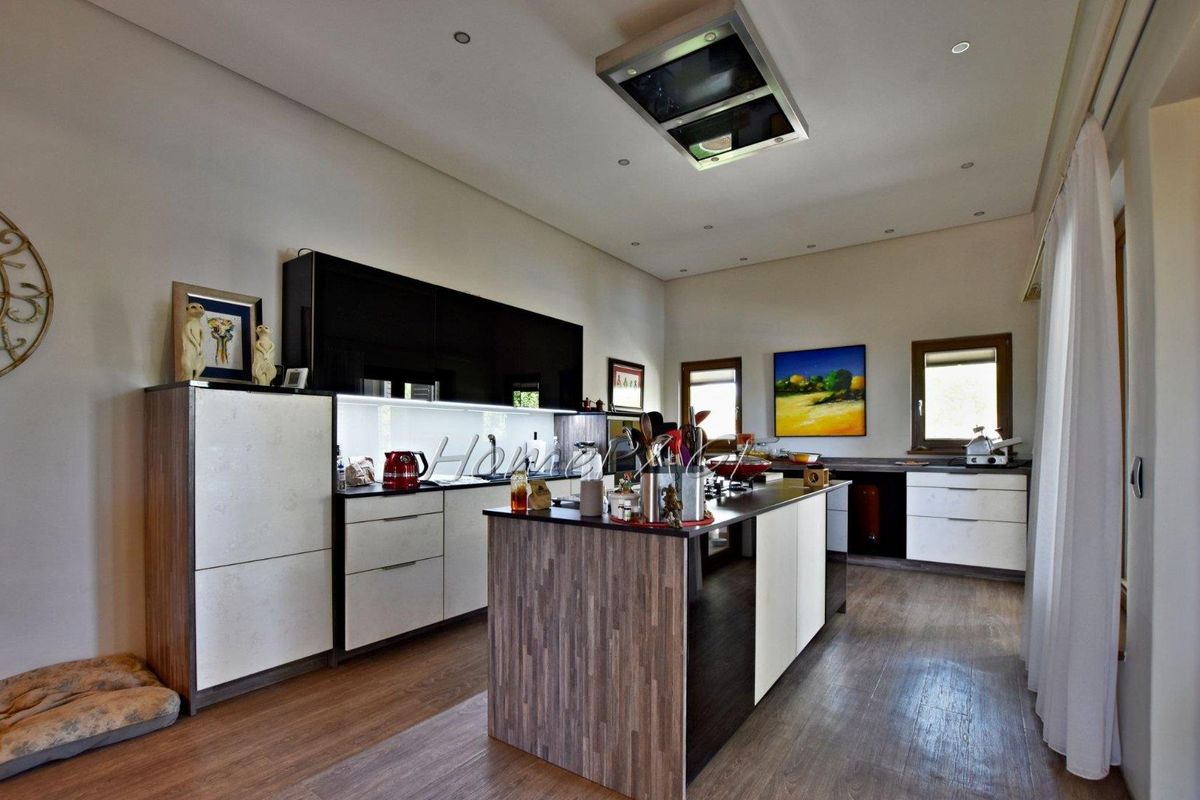 Modern kitchen featuring a central island, high-gloss cabinetry, integrated ceiling extractor fan, and wood-look flooring.