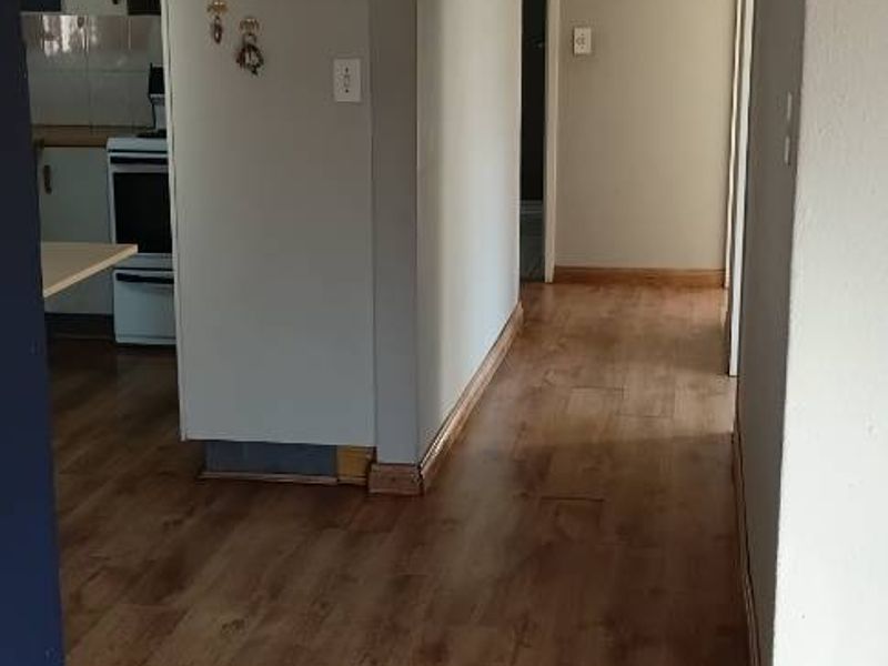 A functional hallway featuring laminate flooring and coved cornicing, providing access to the adjacent kitchen and interior living spaces.