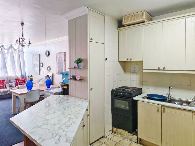 Open-plan kitchen and living area featuring built-in cabinetry, marble-effect countertops, and a tiled backsplash, offering a functional layout for modern living.