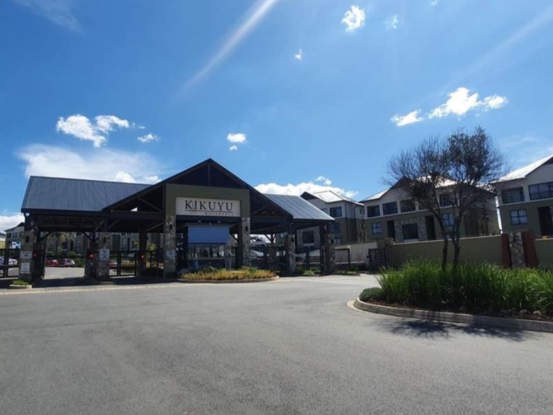 The main entrance and security gatehouse of the Kikuyu apartment complex, featuring stone accents and a modern architectural design.
