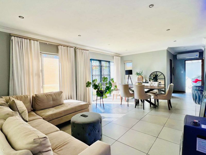 Spacious open-plan living and dining area featuring large format floor tiles, recessed lighting, and direct access to the exterior through sliding doors.