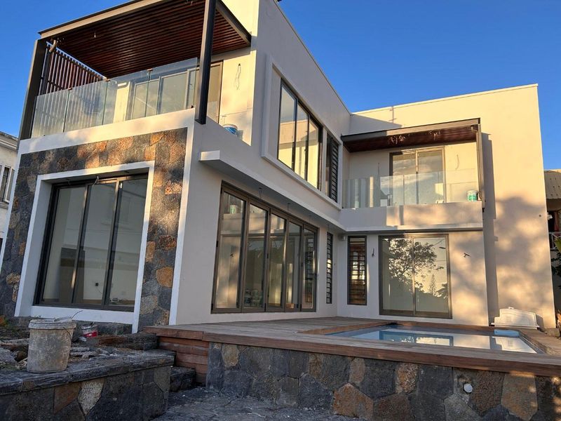 Modern two-story rear exterior featuring a swimming pool, timber decking, stone cladding, and large sliding glass doors leading to upper-level balconies.