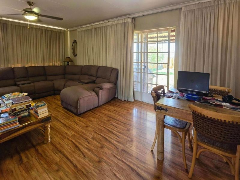 Spacious open-plan living and dining area featuring warm laminate flooring, a ceiling fan, and direct access to the outdoor patio through glass sliding doors.