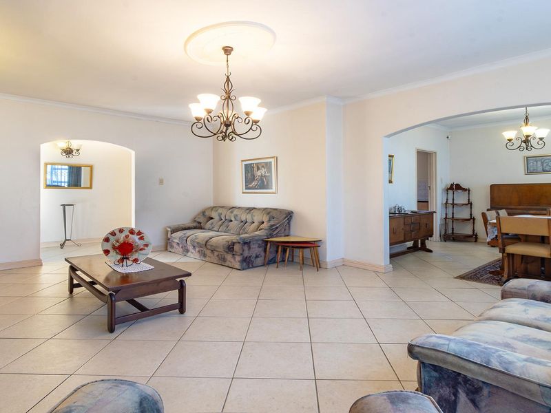 Spacious open-plan living and dining area featuring ceramic floor tiles, decorative ceiling roses, and arched transitions between rooms.