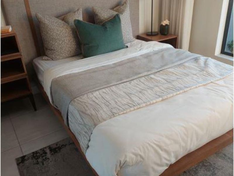 A well-maintained bedroom featuring neutral tiled flooring and a large window that allows for natural light.