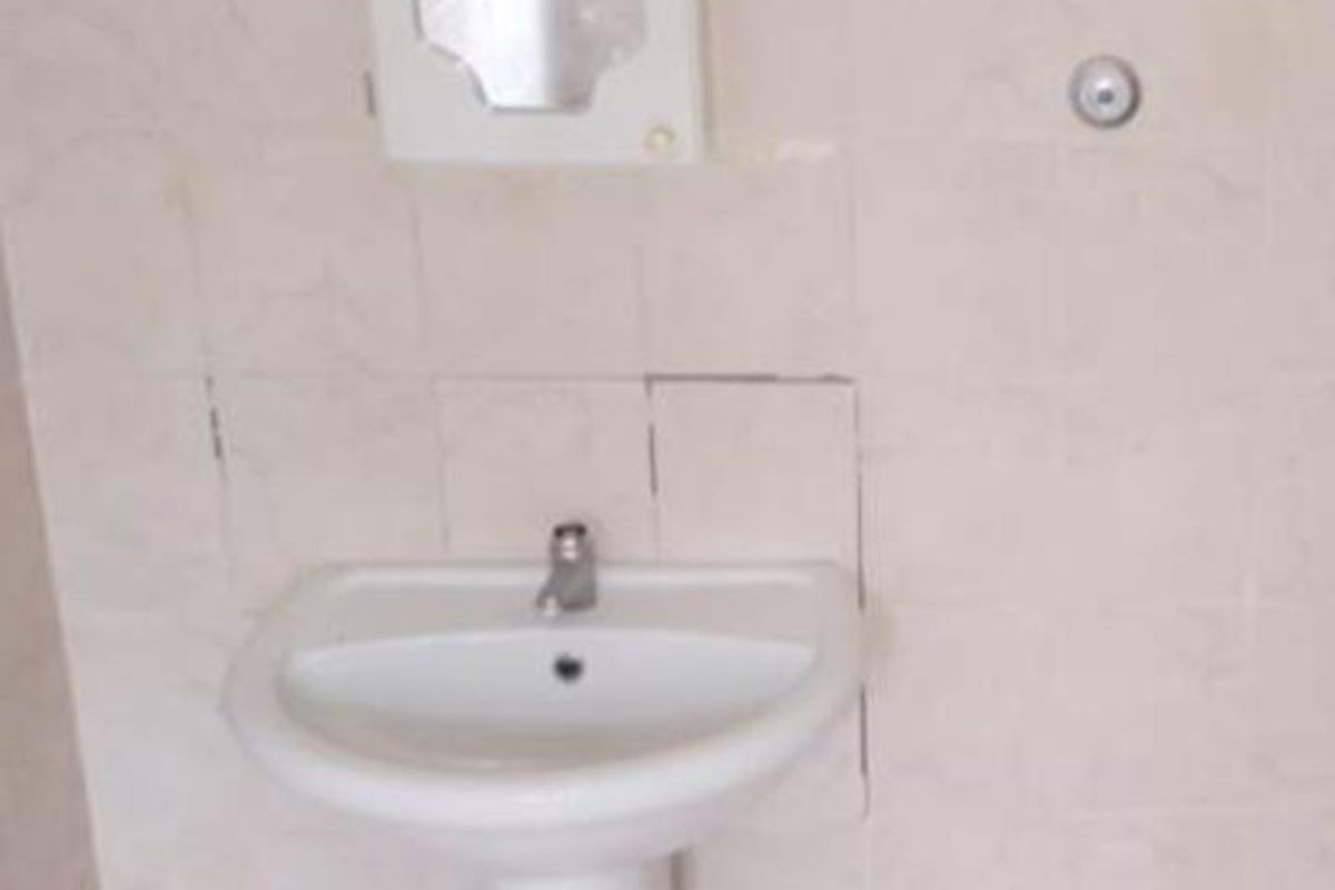 A basic bathroom vanity area featuring a white pedestal sink, wall-mounted mirror cabinet, and tiled wall splashback.
