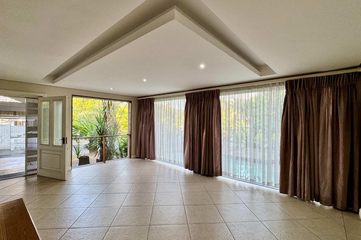 Spacious living area featuring large floor-to-ceiling windows, recessed tray ceiling lighting, and direct access to an outdoor patio area.