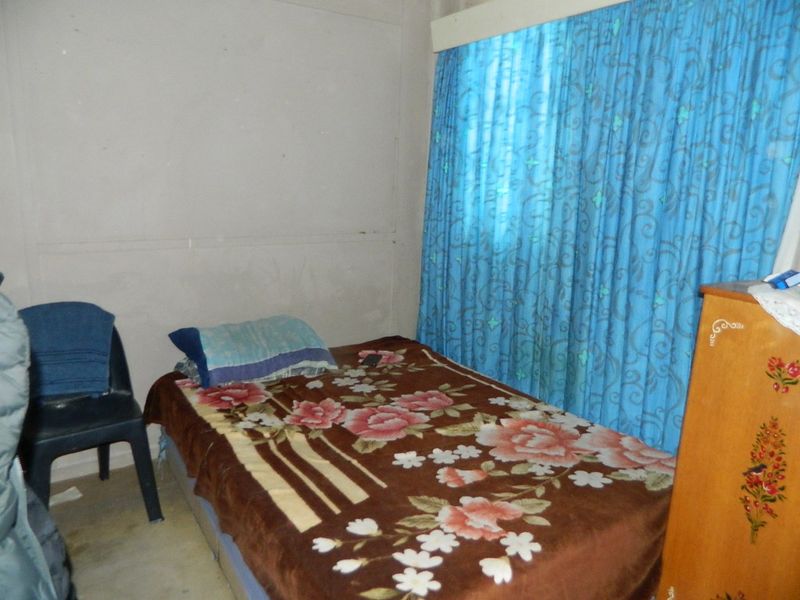 A bedroom featuring plain wall finishes and window coverings, requiring cosmetic updates to improve the overall aesthetic and condition of the space.