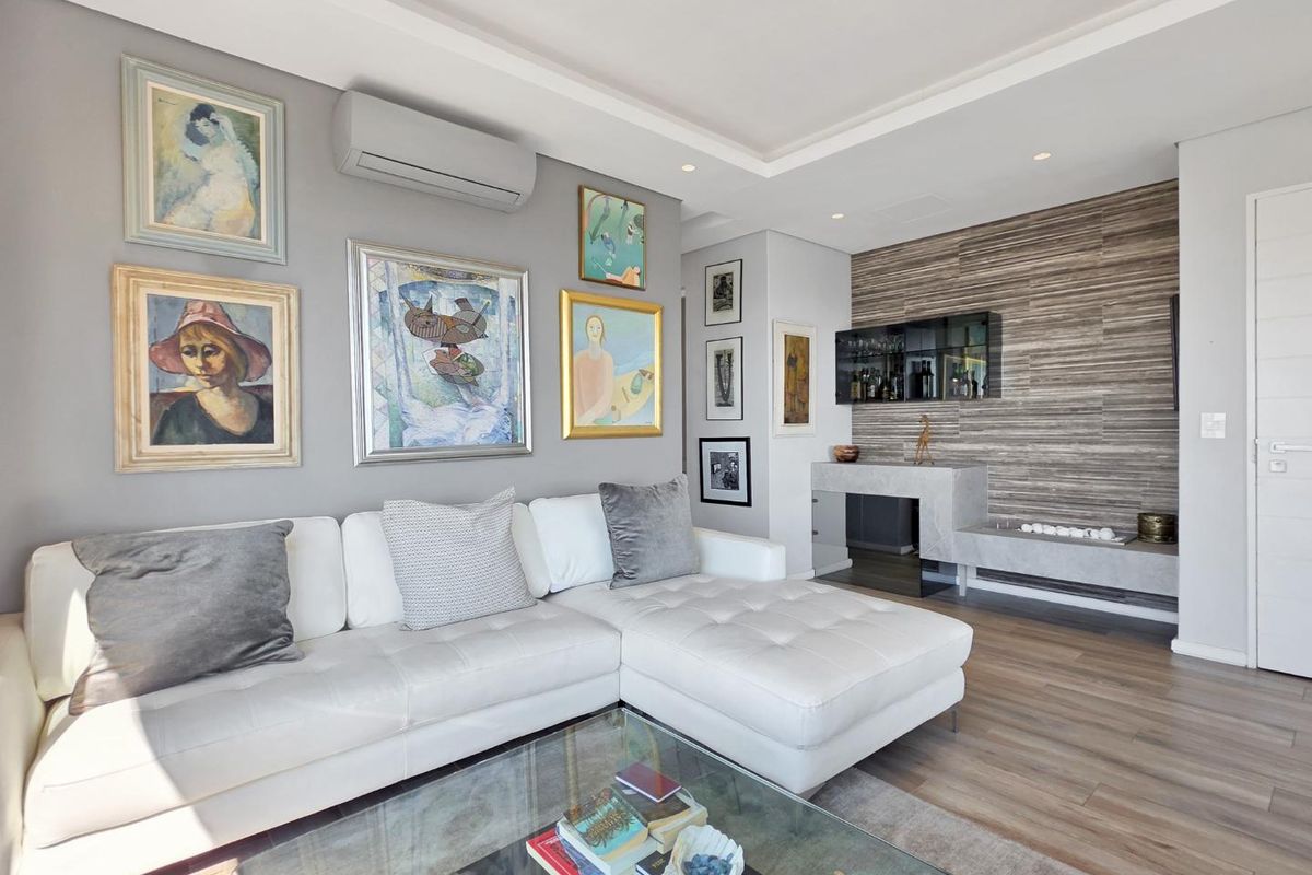 Modern living room featuring a stone accent wall, built-in fireplace hearth, recessed ceiling lighting, and wall-mounted air conditioning.