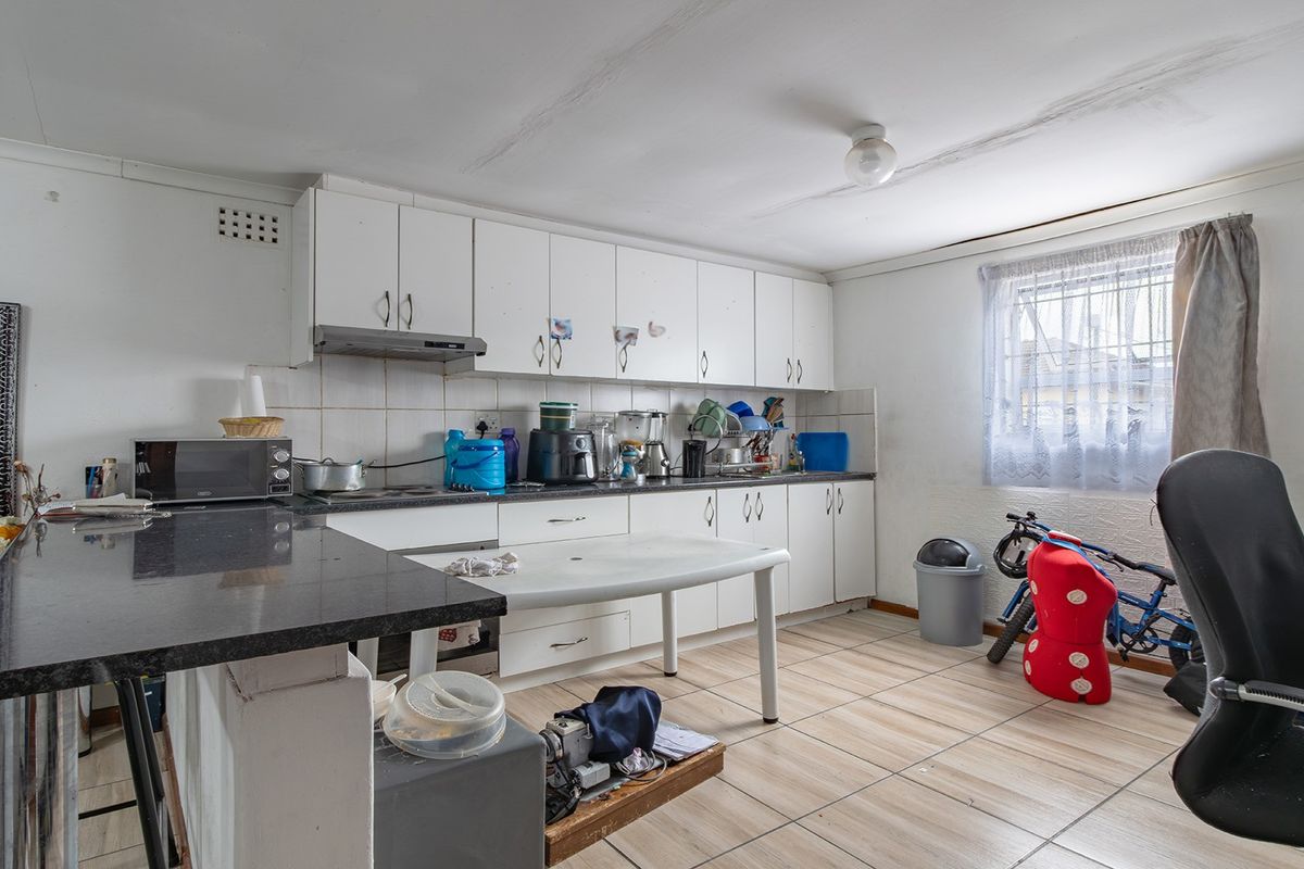 A dated kitchen featuring white cabinetry, granite countertops, and tiled flooring, currently showing signs of ceiling water damage and requiring cosmetic updates.