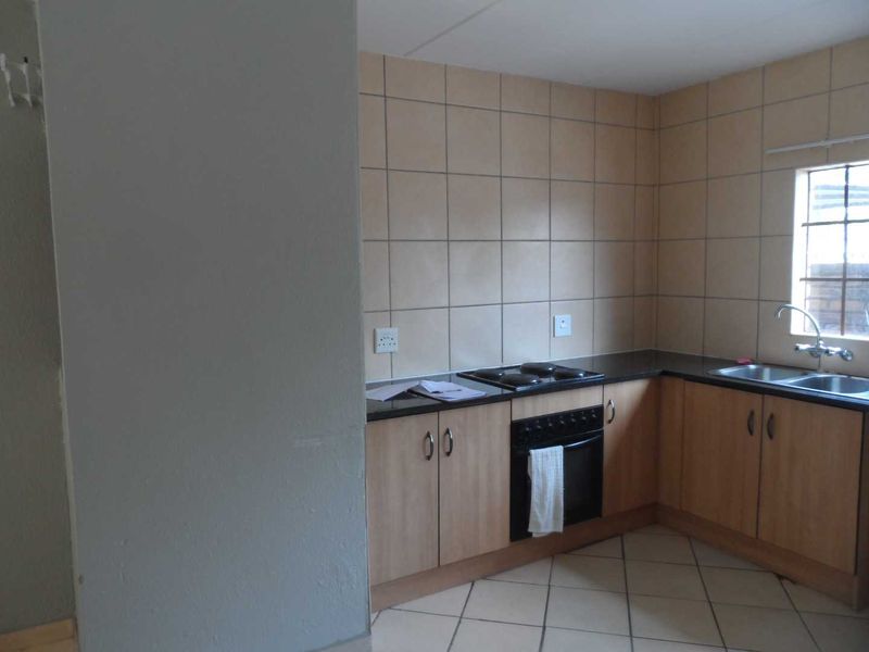 A functional kitchen featuring laminate cabinetry, granite countertops, built-in oven, electric hob, and double bowl sink with tiled splashbacks.