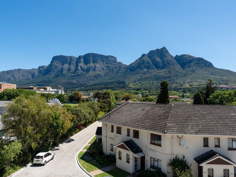 Elevated view overlooking a residential complex with a paved driveway and a scenic backdrop of the mountain range.