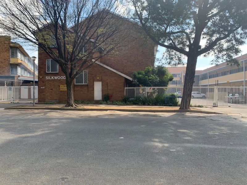 Street view of the Silkwood apartment complex featuring a brick facade, secure gated entrance, and perimeter fencing.