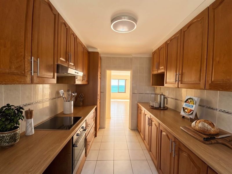A galley-style kitchen featuring warm-toned wooden cabinetry, laminate countertops, ceramic tile backsplash, and built-in appliances, leading to a bright living area with ocean views.