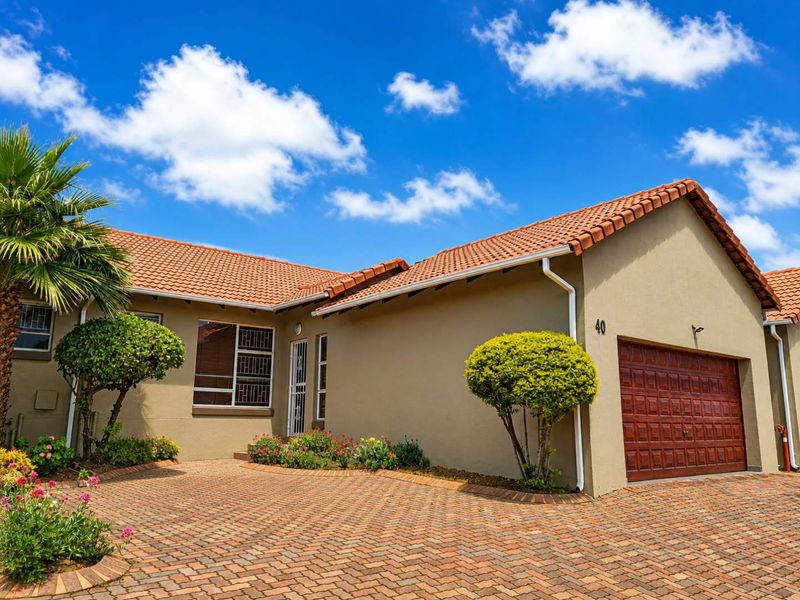 Front elevation of a townhouse featuring a tiled roof, brick paved driveway, and a double garage with secure access.