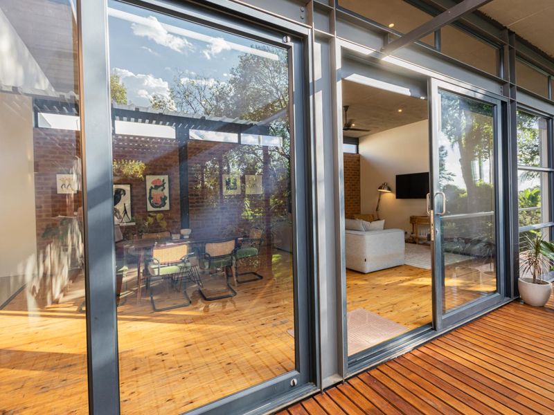 A modern covered patio featuring timber decking and large sliding glass doors that provide a seamless transition to the interior living and dining areas.