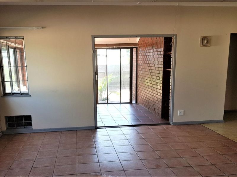 An empty living area featuring tiled floors, exposed brick accents, and a sliding glass door leading to an outdoor space.
