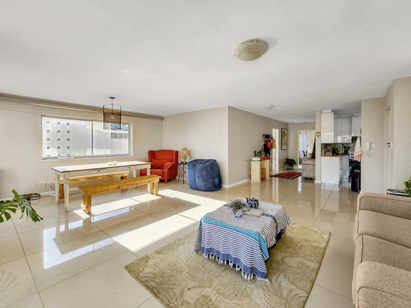 Spacious open-plan living and dining area featuring polished tiled flooring and a functional kitchen with white cabinetry.