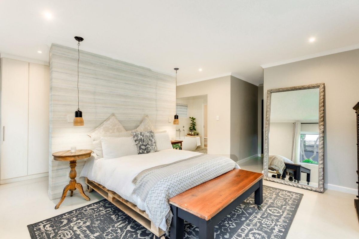 Spacious bedroom featuring a textured feature wall, built-in cabinetry, and an open-plan layout leading to an en-suite bathroom area.