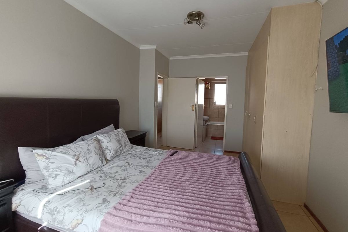 A bedroom featuring built-in cupboards and an en-suite bathroom with tiled flooring.